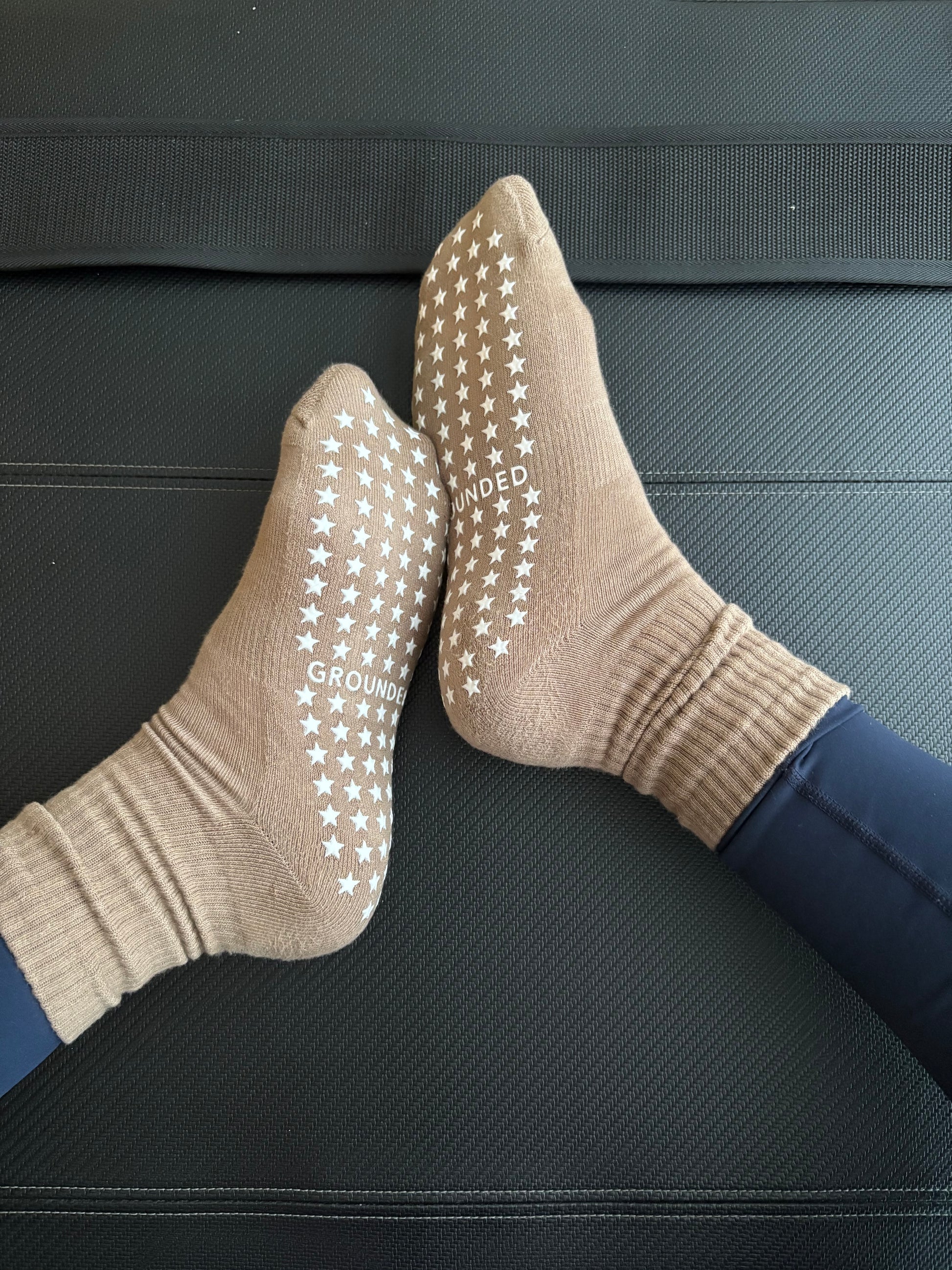 Beige grip socks with star patterns on a black pilates reformer.