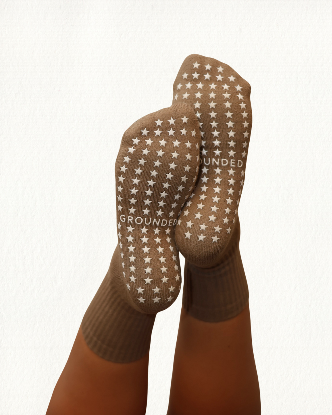 Brown barre socks with star patterns and 'GROUNDED' text on a white background