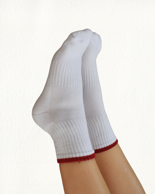 White grippy socks with red trim on a white background