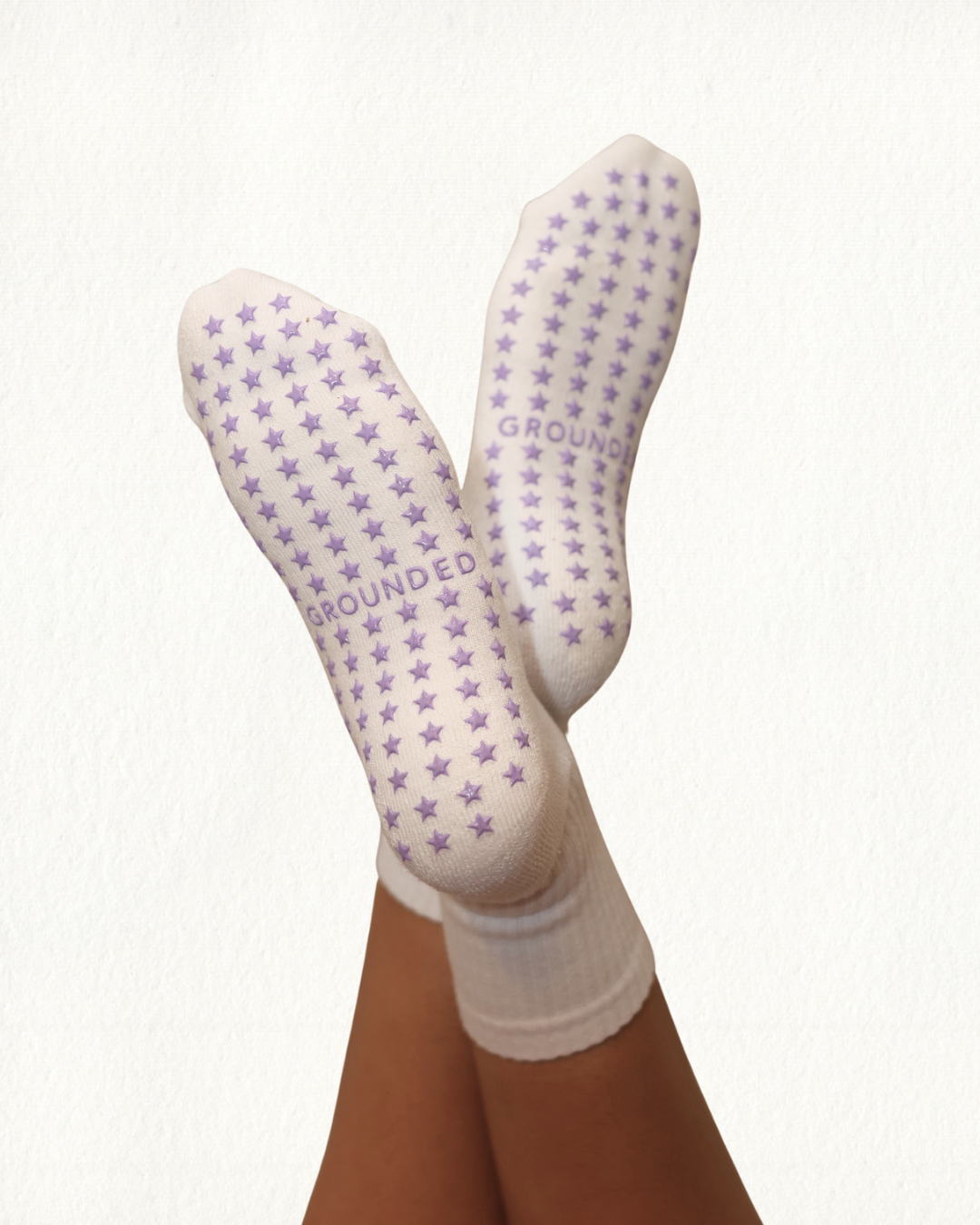 White yoga and pilates socks with purple star patterns and 'GROUNDED' text on a white background