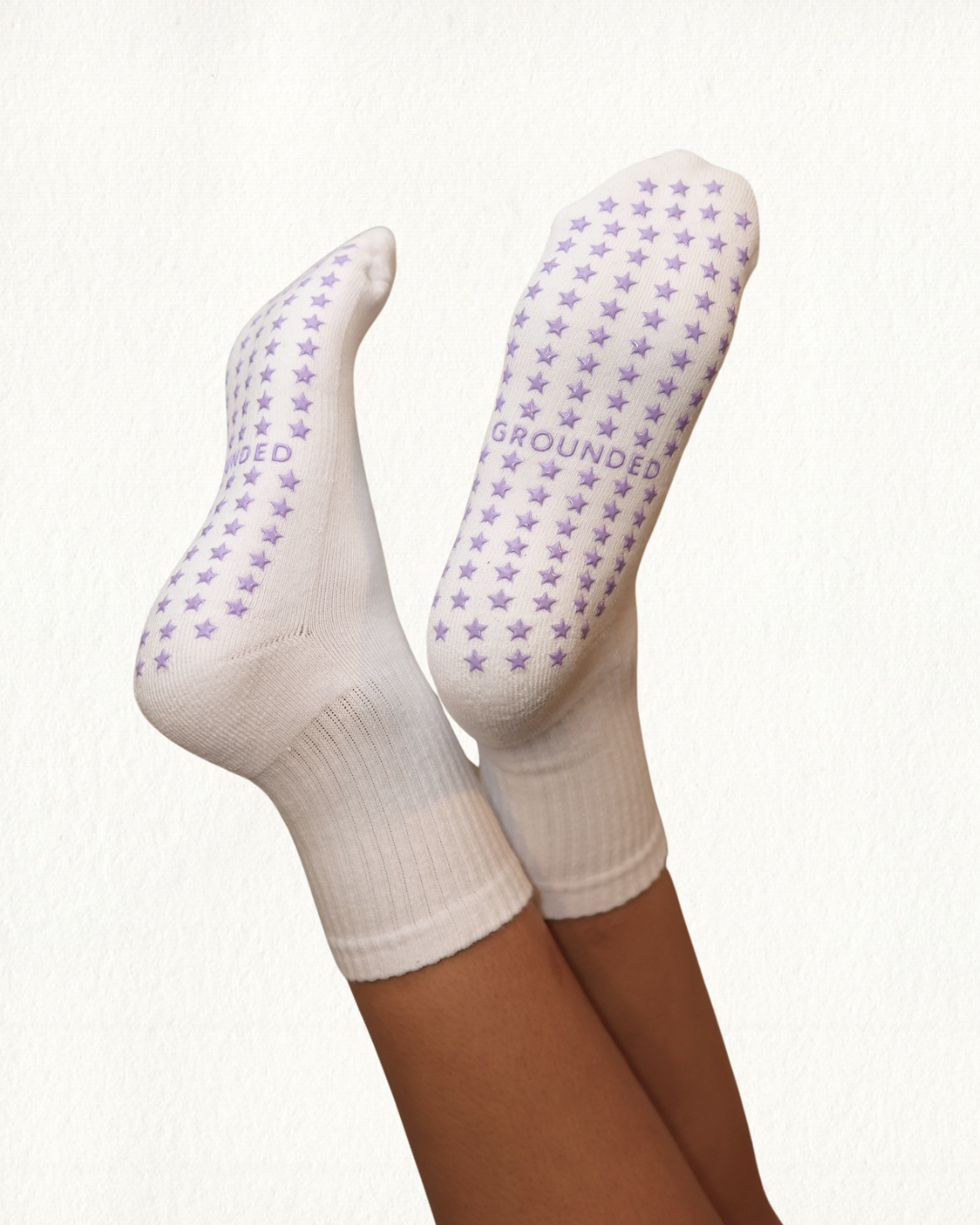 White grip socks with purple star patterns and 'GROUNDED' text on a white background