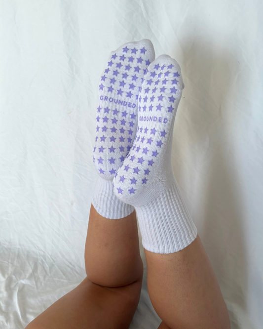 White grip socks with purple star patterns worn by a person on a white background