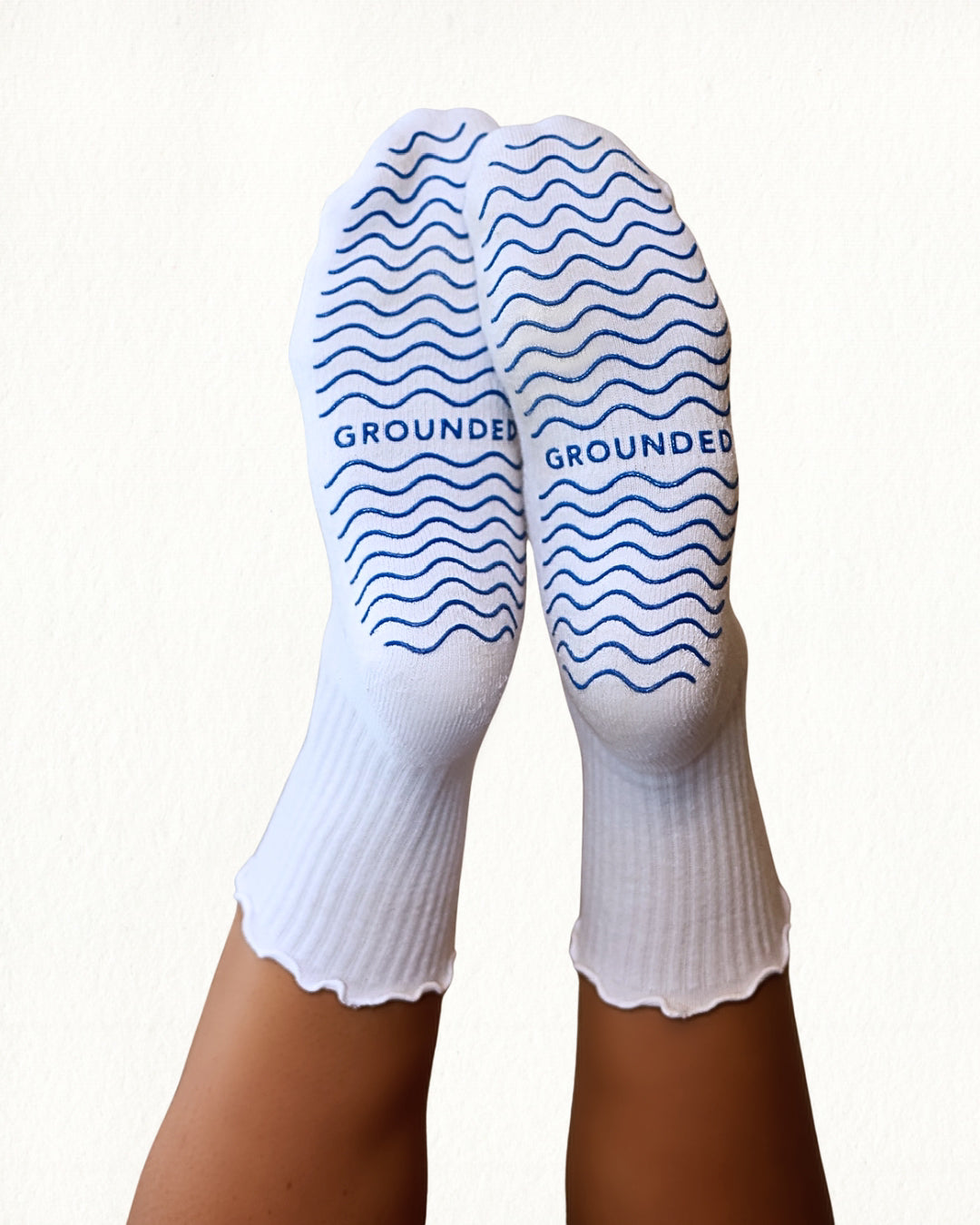 White pilates socks with blue wave patterns and 'GROUNDED' branding on a white background