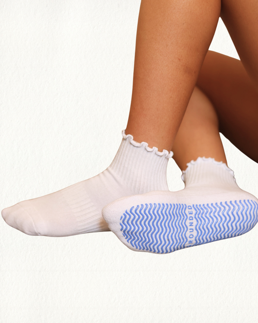 White frill grip socks with blue and white striped sole on a white background