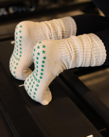 Beige scrunch Pilates socks with green star patterns on a black Pilates reformer