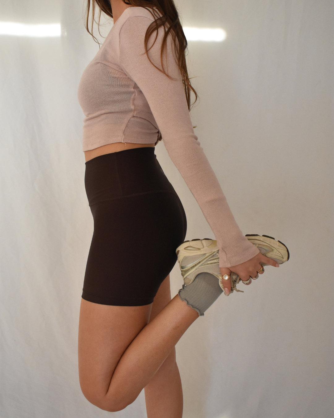 Person wearing a beige long-sleeve crop top and black high-waisted shorts and cute ruffle grip socks