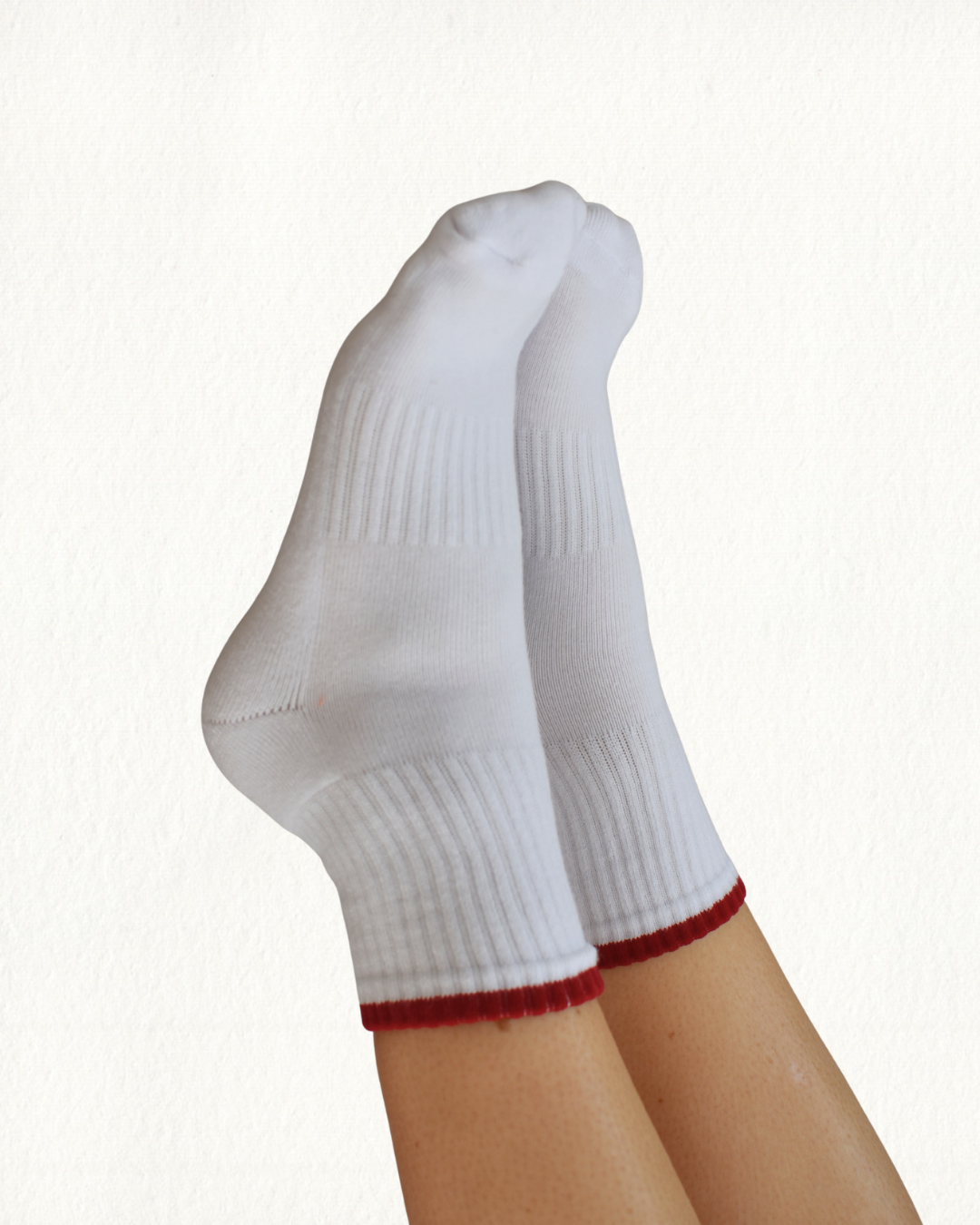 White grippy socks with red trim on a white background