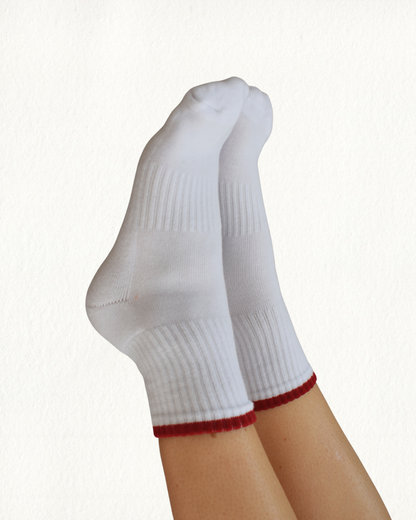 White grippy socks with red trim on a white background