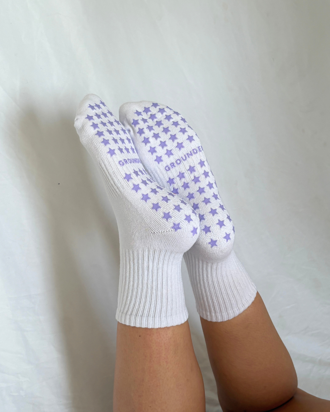 White grippy socks with purple star patterns on a white background