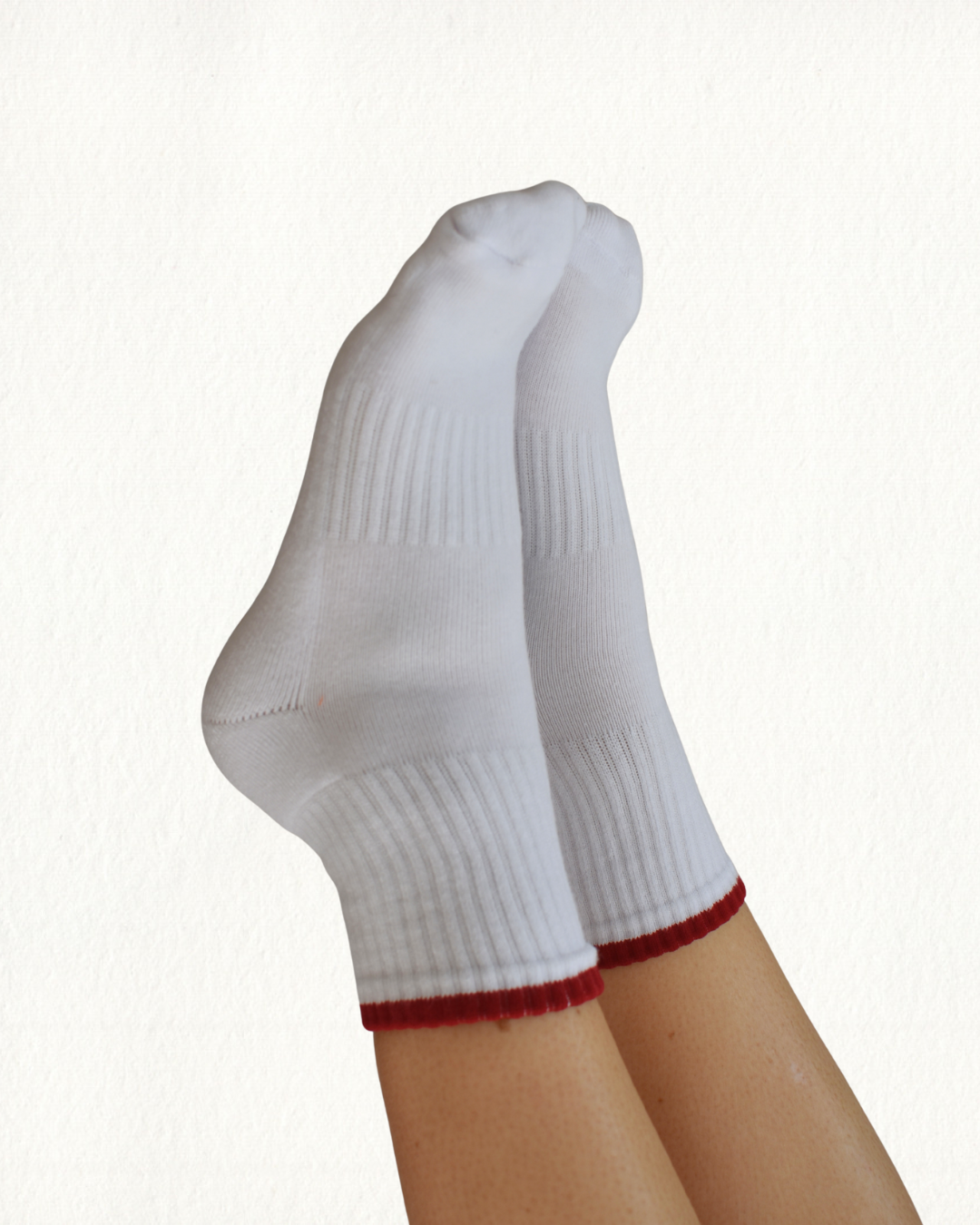 White grippy socks with red trim on a white background