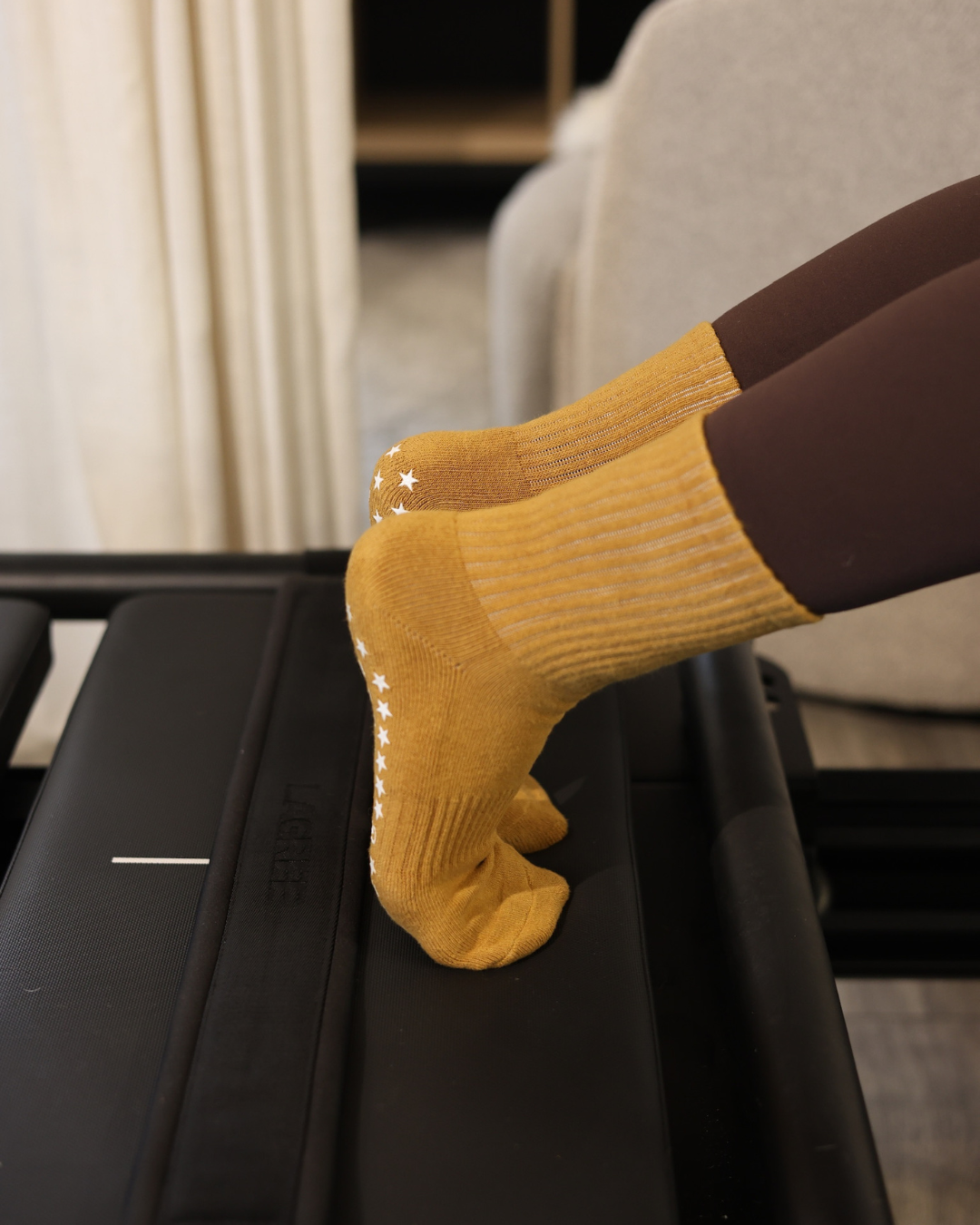 Person wearing mustard yellow socks with white stars on a black surface.