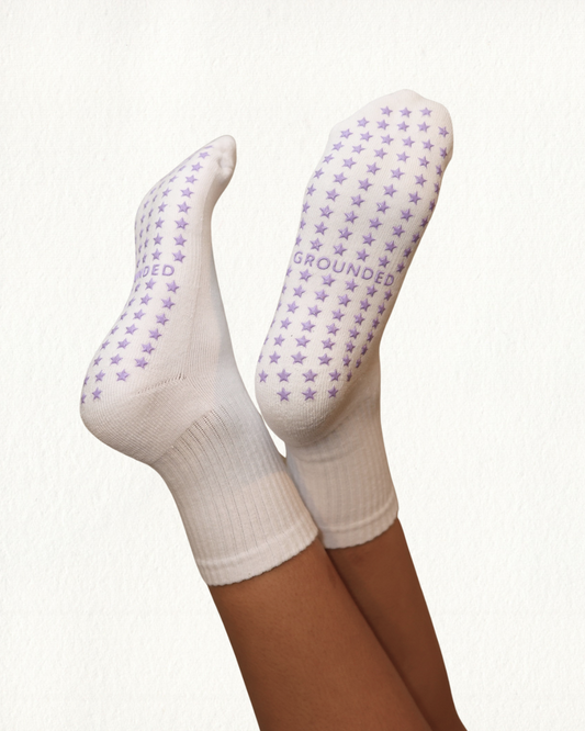 White grip socks with purple star patterns and 'GROUNDED' text on a white background