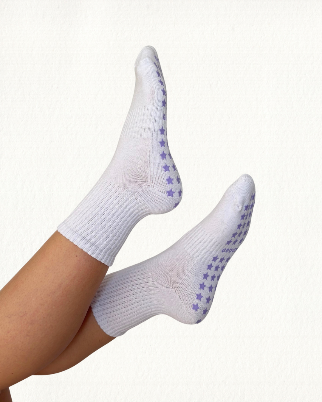 White pilates socks with purple star grips on a white background