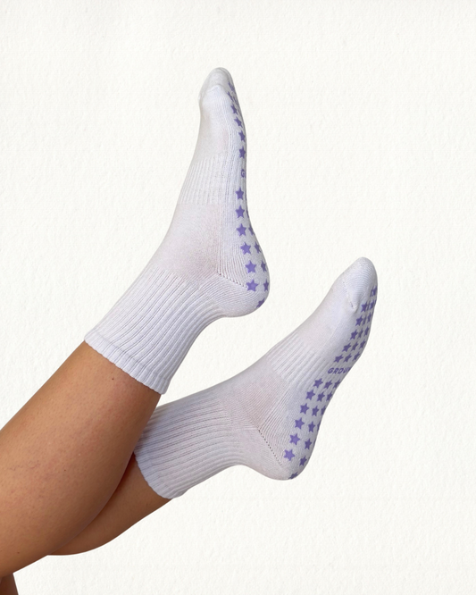 White pilates socks with purple star grips on a white background