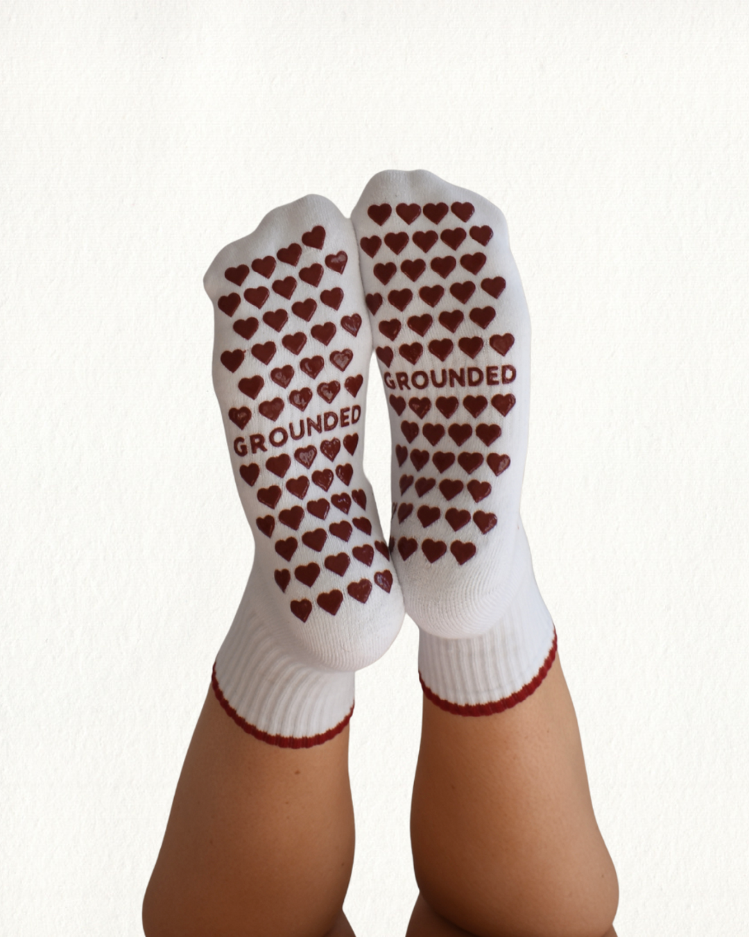 White grip socks with red heart grip patterns and 'GROUNDED' text on a white background