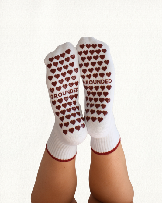 White grip socks with red heart grip patterns and 'GROUNDED' text on a white background