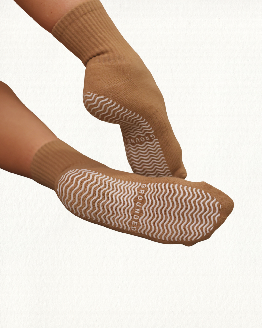 Brown Pilates socks with wavy grip pattern on a white background