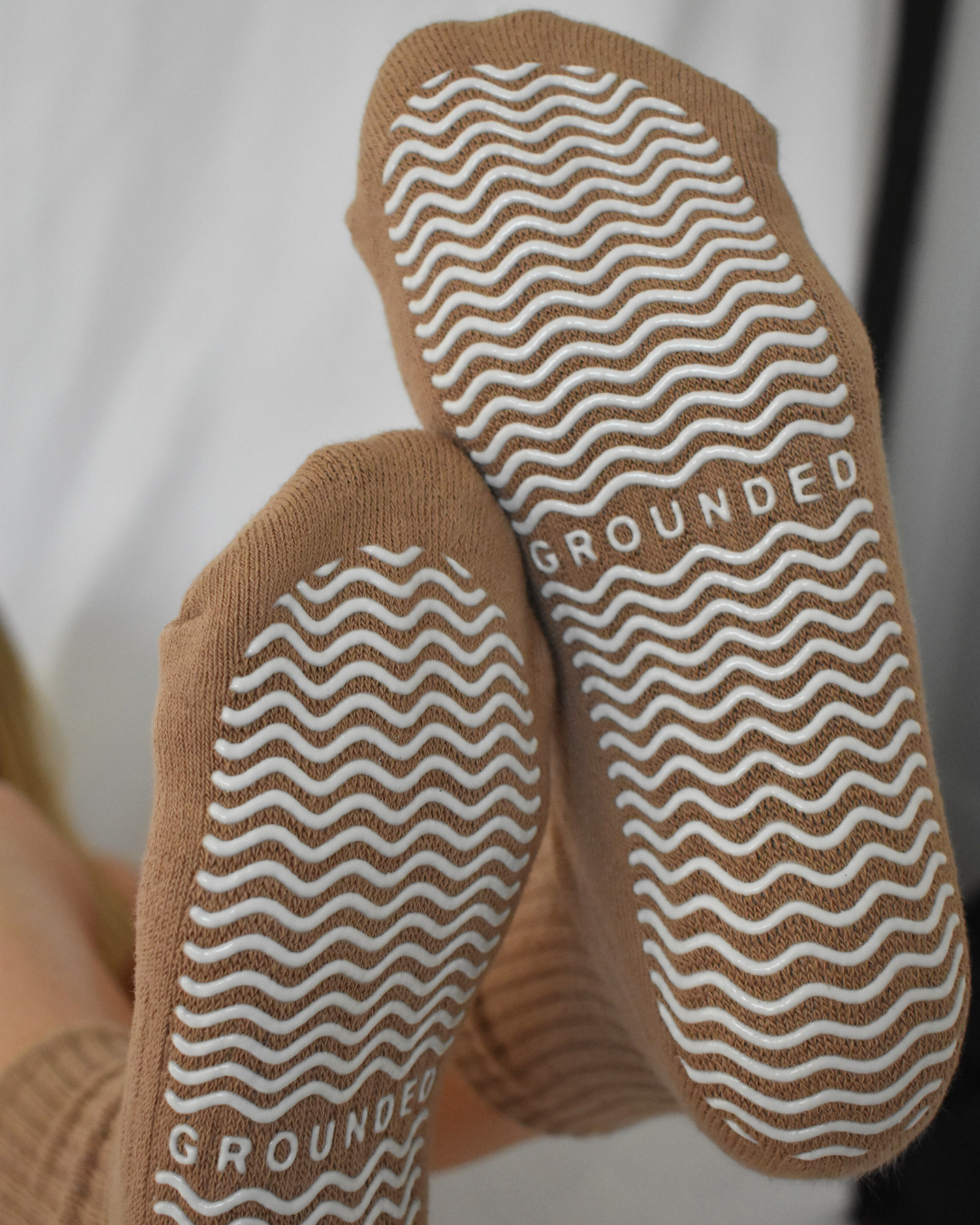 Close-up of brown socks with textured sole and 'GROUNDED' branding.