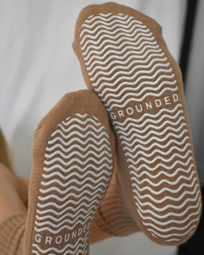 Close-up of brown socks with textured sole and 'GROUNDED' branding.