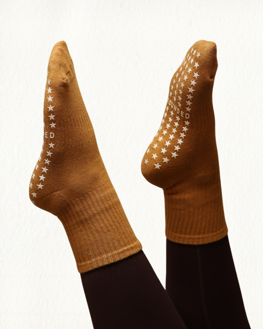 Mustard barre socks with star grip patterns on a white background.