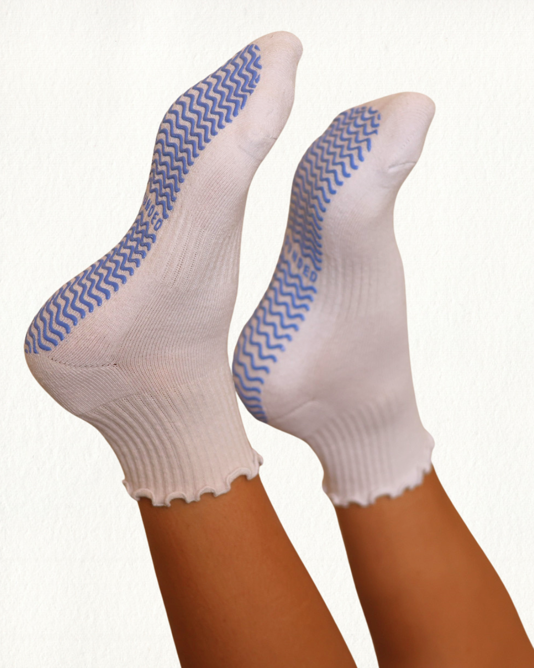 White Pilates grip socks with blue patterns on toes against a white background
