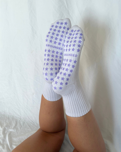 White grip socks with purple star patterns worn by a person on a white background