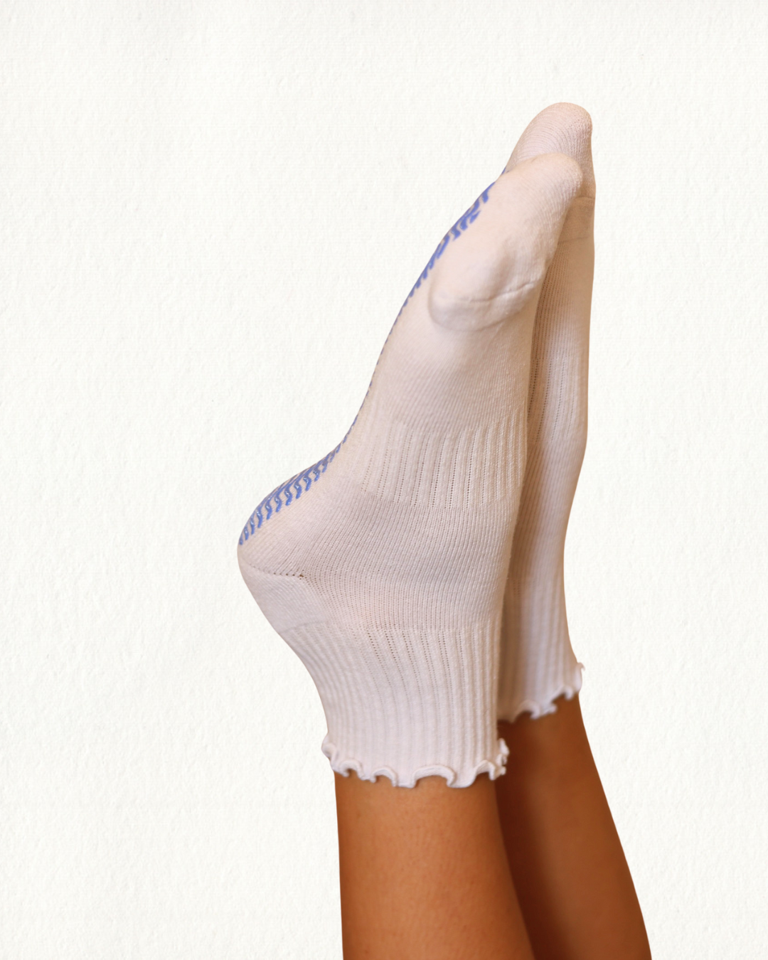 White frill Pilates socks with blue trim worn by a person on a white background