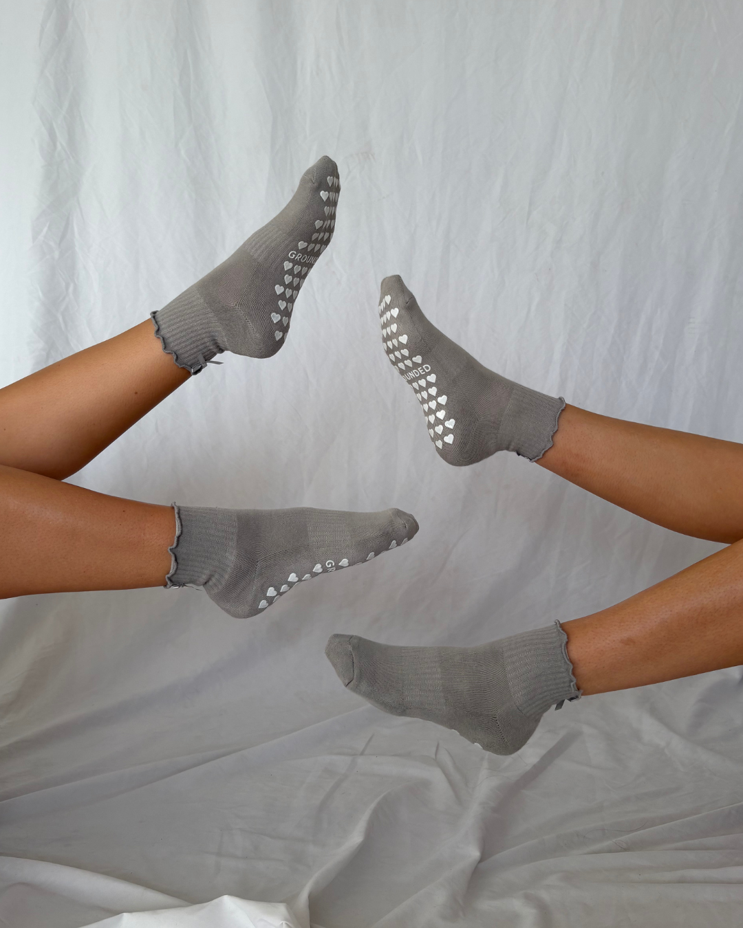 Gray ruffle pilates socks with textured sole worn by a person on a white background