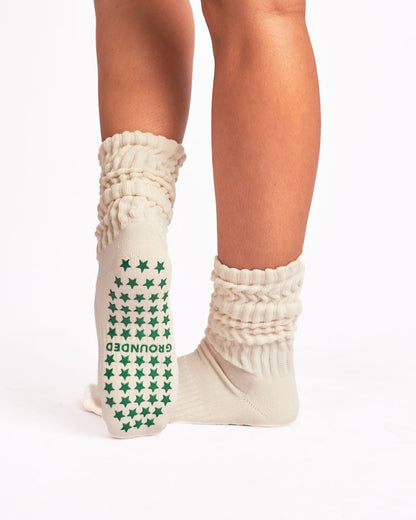 Cream scrunch grip socks with green star pattern worn by a person on a white background