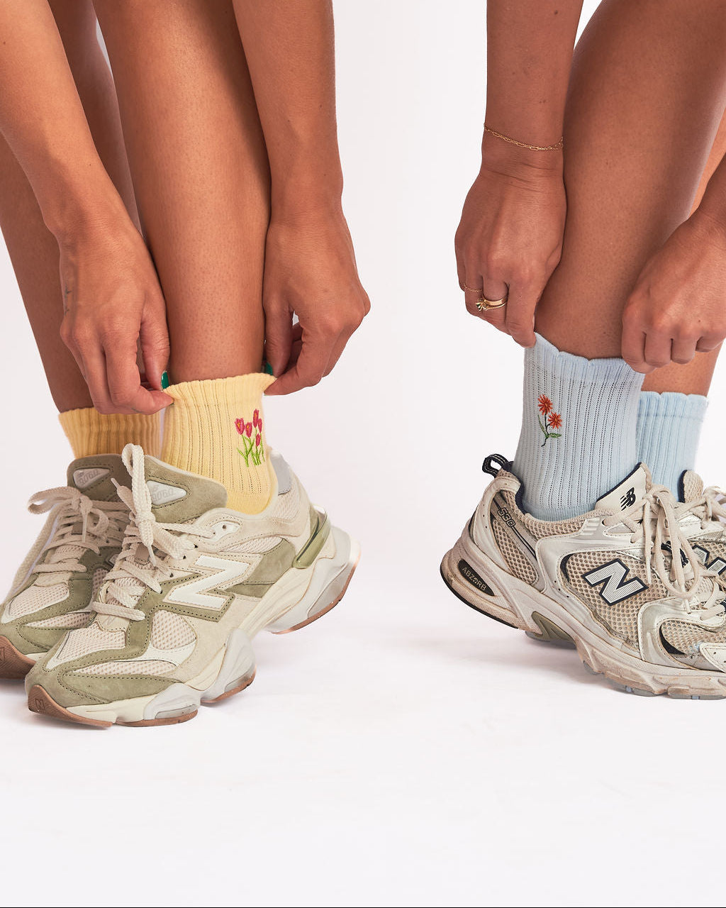 Two people wearing sneakers and flower embroidered grip socks
