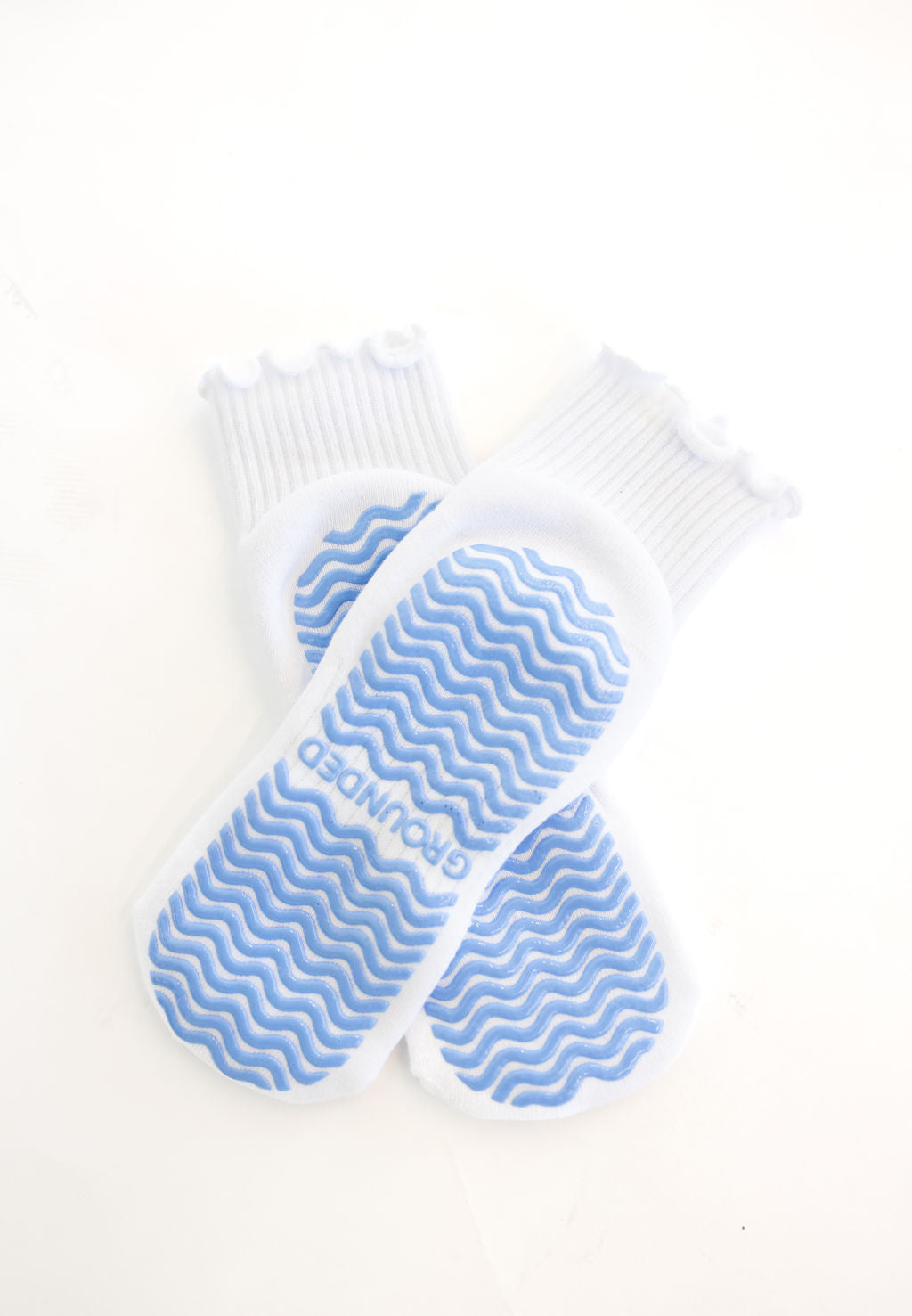 White ruffle grip socks with blue grips on a white background