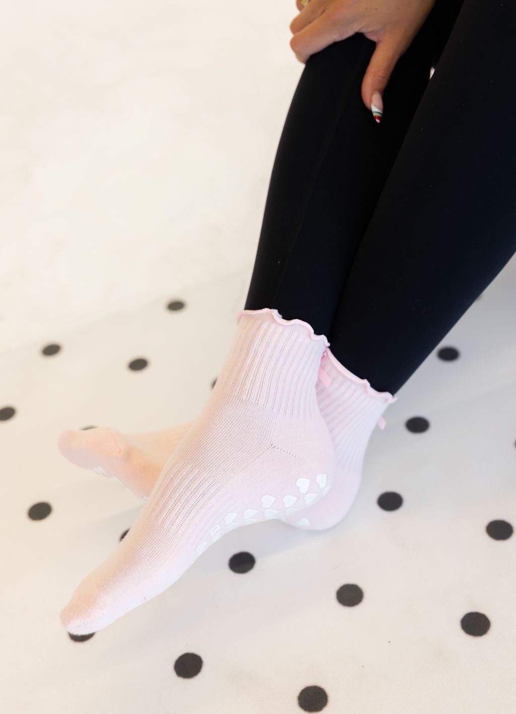 Person wearing light pink pilates socks on a polka dot surface