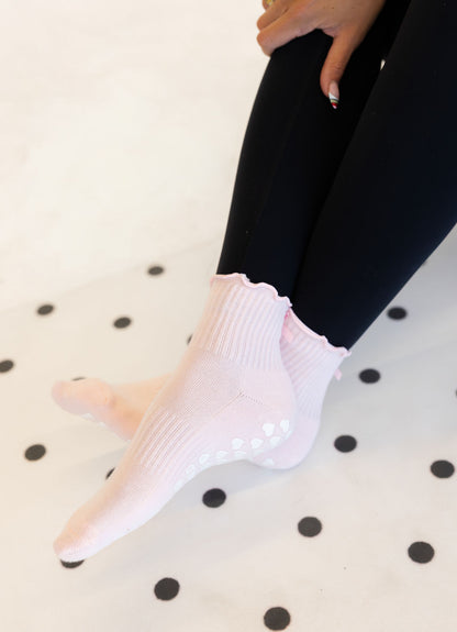 Person wearing light pink pilates socks on a polka dot surface