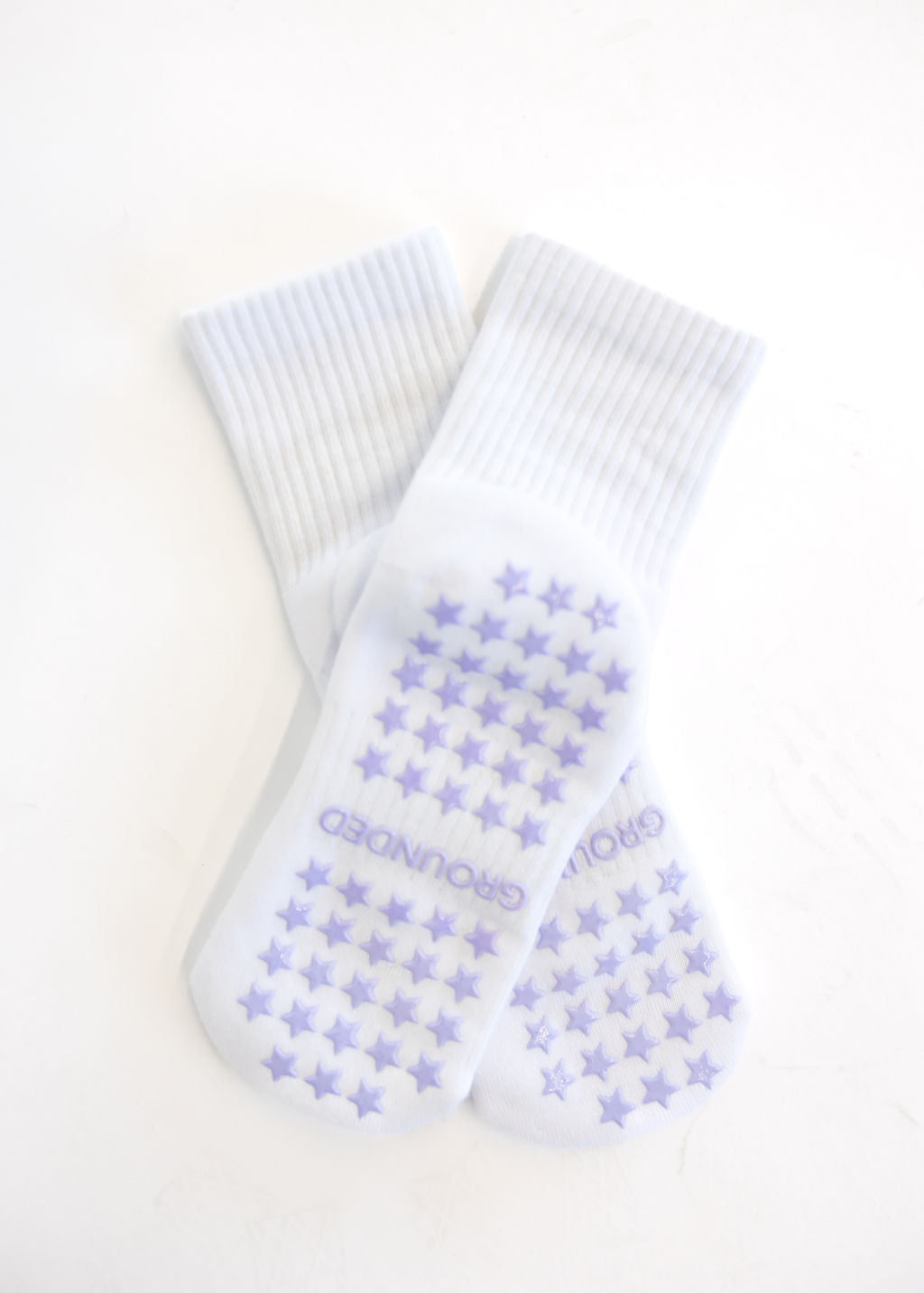 White crew grip socks with purple star pattern and brand name on a white background