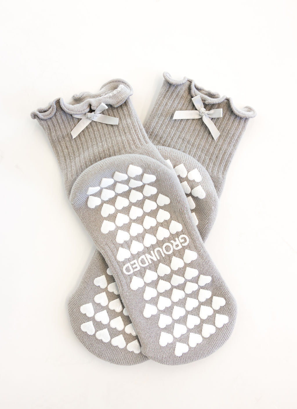 Gray pilates grip socks with white heart patterns and 'GROUNDED' branding on a white background