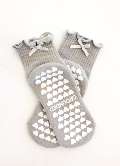 Gray pilates grip socks with white heart patterns and 'GROUNDED' branding on a white background