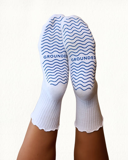 White pilates socks with blue wave patterns and 'GROUNDED' branding on a white background
